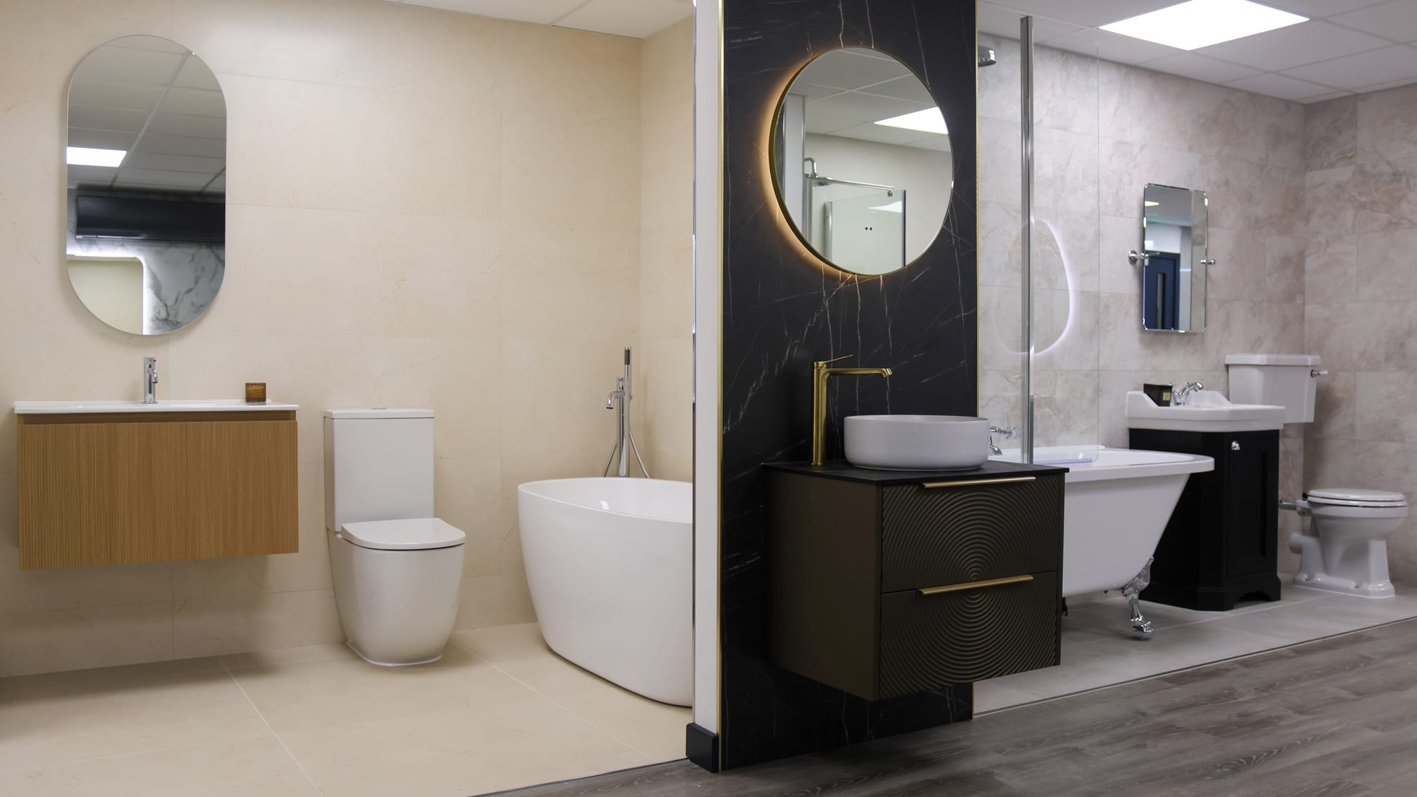 Pochin Eastbourne showroom with a freestanding bath, oak vanity, black marble pillar with brass tap and a traditional roll-top bath suite